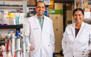 photo of two people standing in labcoats labeled "Breaking." They are smiling and appear to be in a lab setting.