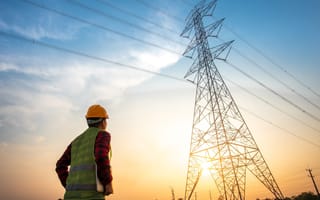 A utility worker stares up at a power line.