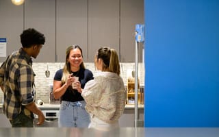 CarGurus team members gathered together in the office kitchen, talking and laughing.