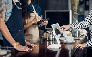 Employees take a customer's order with a tablet at a restaurant.