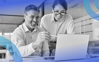 A man and a woman are looking at a computer screen and are smiling.