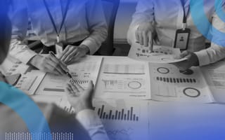 A close-up, neck-down view of three business people poring over graphs and charts at a table.