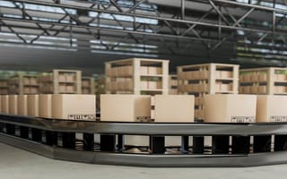 A conveyor belt carries boxes through a manufacturing warehouse.