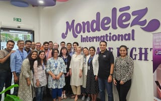 A group of Mondelēz employees stand in front of a graphic featuring the company’s logo.