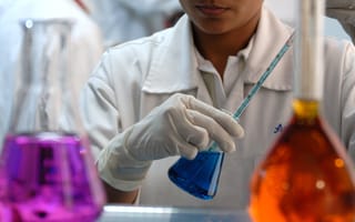 A pharma scientist holds a pipette in an Erlenmeyer flask.