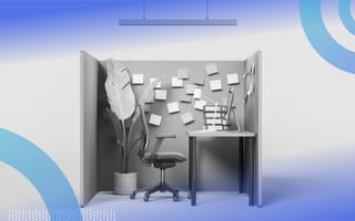 A side view of a cubicle with a large potted plant in the corner, rolling chair, desk, computer and sticky notes on the walls.
