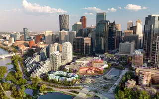 An aerial view of the Calgary skyline on a sunny day, with the Bow River peaking through the left side.