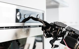 Robotic hand with a finger extended, programing an oven