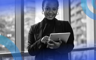 A Black business owner is standing and holding a tablet.