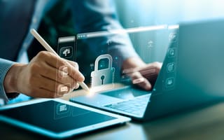 A digital illustration of a padlock hovers over a laptop and a tablet to represent cybersecurity.