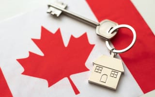 A house keychain on top of the Canadian flag.