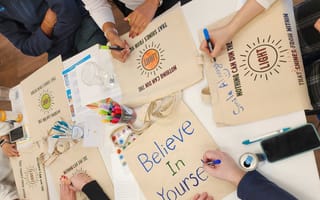 Looking down on a table where CarGurus' team members are decorating bags with inspirational messages.