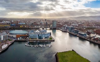 An aerial view of Belfast that showcases sun rays through gray clouds.