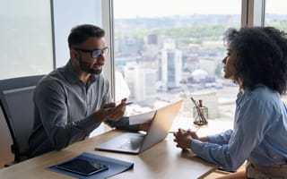 two professionals talking at a desk
