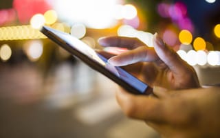 Close-up photo of woman's hand holding her mobile phone in the street.