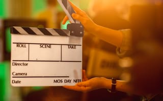 Close-up of hands holding clapperboard.