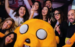 Warner Bros. Discovery team members pose with a large plush character of Jake the Dog from Adventure Time.