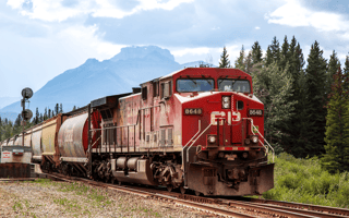 A Canadian Pacific locomotive at the station in Banff with forests and mountains in the distance