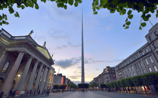 The Dublin Spire monument is visible against an early sunset.