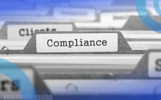 A close-up of files in a filing cabinet, with the file in focus labeled “compliance.”