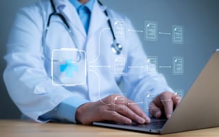Physician typing on a computer displaying digital healthcare symbols.