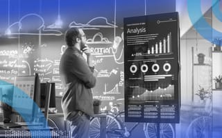 A marketer stands with a contemplative hand on his chin, staring at a big hologram displaying analytics.