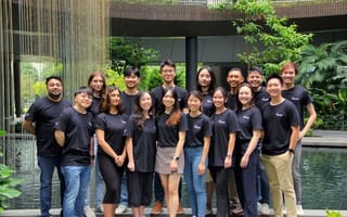 A group of 16 employees in Omni HR t-shirts stand together in two rows of eight smiling at the camera.