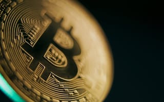 An illustration of a gold coin featuring the Bitcoin symbol against a black background.