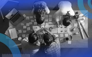 An aerial view of a team of four designers poring over papers and sticky notes.
