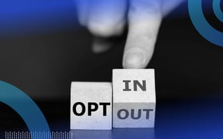 Two wooden cubes, the first reading “OPT” and the second being tilted by a person’s hand so you can see one side that reads “IN” and another that says “OUT.”