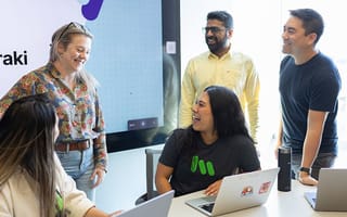 Cisco Meraki team members laughing as they discuss a project together in the office