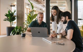 Grammarly team members look at information on a laptop screen while working together in the office