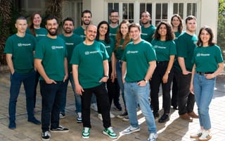A group of employees all wearing green shirts that say Hopper on the front stand together for a photo.