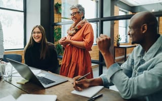 Professionals laughing while discussing a project together in an office