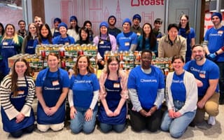 Toast team members posing for a group photo while wearing company-branded T-shirts in the office during a volunteering event