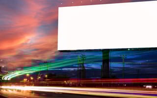 A blank billboard sits alongside a busy roadway.