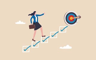 A woman climbs a stairway of checked boxes to reach a target.