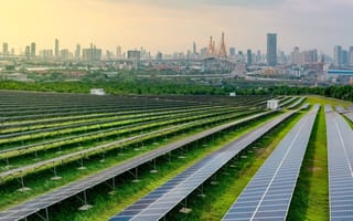 Renewable energy facility with rows of solar panels near city.