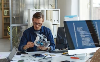 A tech employee sits at a desk working on a VR headset