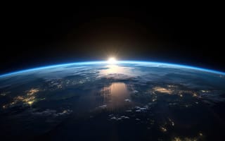 A view of earth from space, with the sun rising over the horizon line.