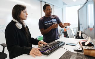 Two Capital One employees work in front of a computer monitor.