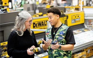 A Lowe's employee is shown assisting a customer while holding a handheld device.