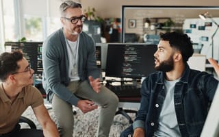 Three software engineers discuss an ongoing project in an office
