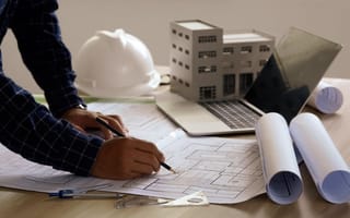 worker's hands with blueprints and hard hat