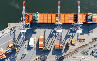 Shipping containers are loaded on to a cargo vessel docked at a port.