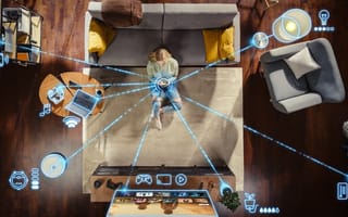 Bird's eye-view of person sitting on couch with devices connected by blue lines.