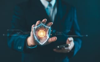 A person in a suit holding a smartphone displays a glowing shield hologram with "AI."