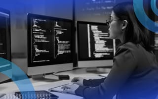 A web developer writes code with multiple monitors