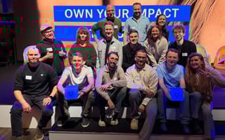 Several Dropbox employees pose for a group photo while seated on a stage during a company event