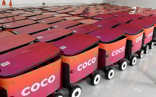 A fleet of red delivery robots is shown.